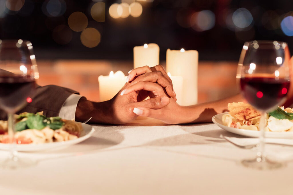 Ein paar hält sich an einem romantisch gedeckten Tisch die Hände.
